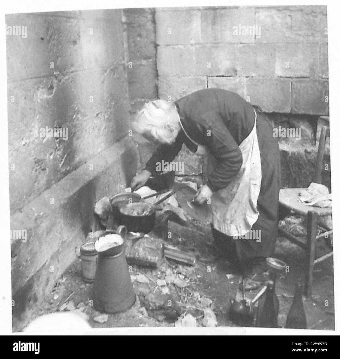 LA CATTEDRALE DI CAEN RIPARA I SENZATETTO - all'interno del quartiere della Cattedrale una anziana donna francese cucina un pasto. , British Army, 21st Army Group Foto Stock