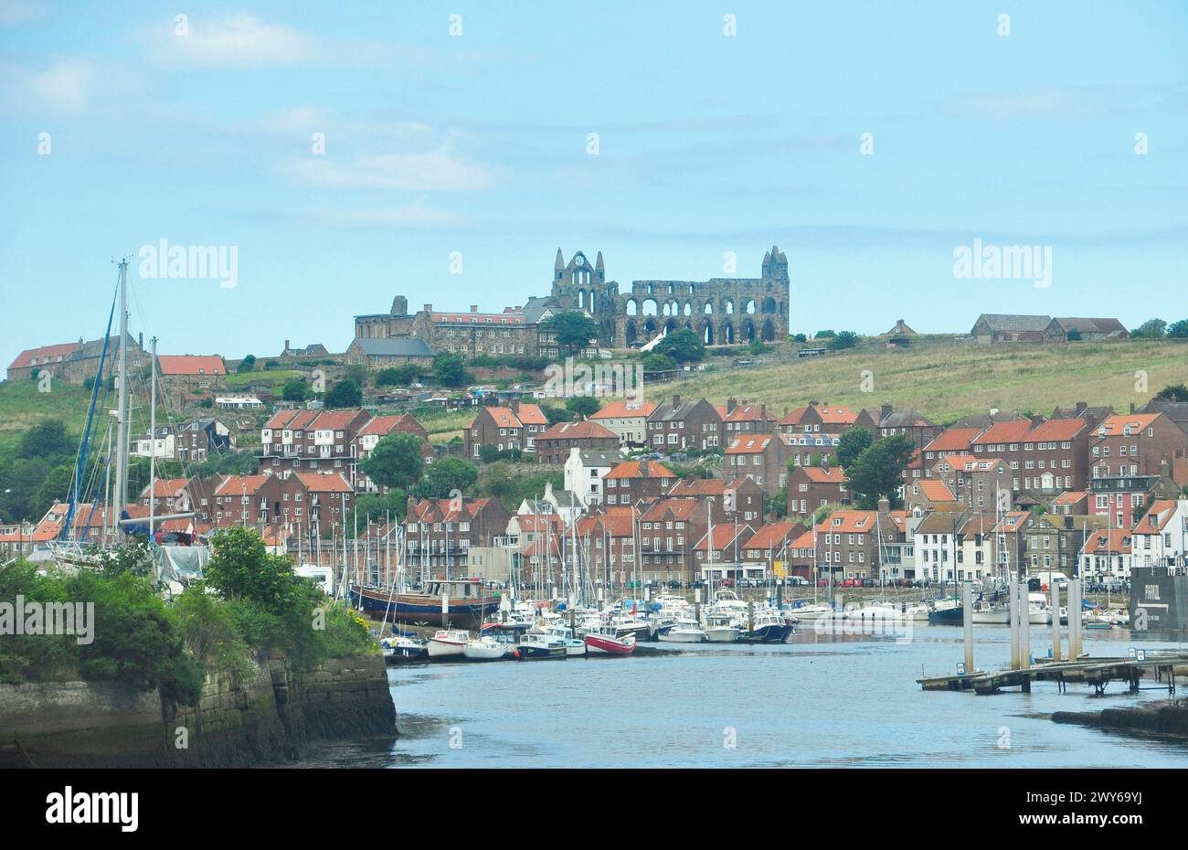 Le rovine dell'abbazia di Whitby si affacciano sul trafficato porto di lavoro e svago all'estuario del fiume Esk.Yorkshire, Inghilterra, Regno Unito Foto Stock