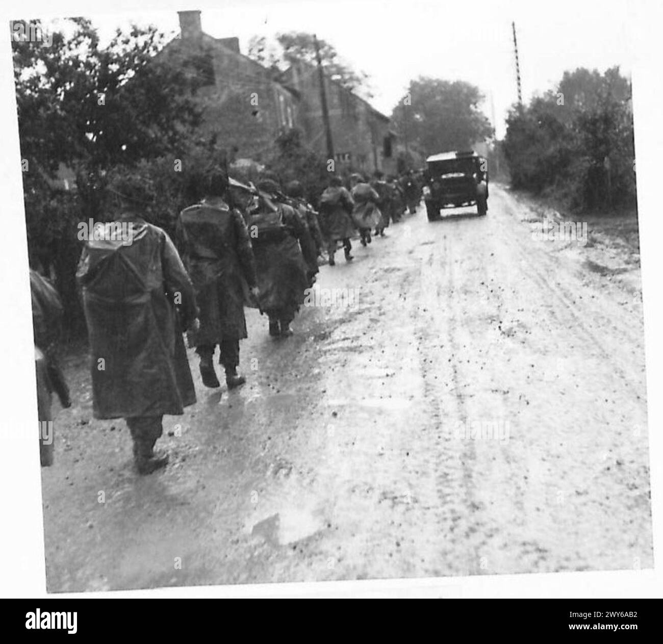 I paracadutisti dell'esercito britannico del 21st Army Group marciano sotto la pioggia tra Troarn e Banneville, uscendo dal fronte durante le operazioni in Normandia. Foto Stock