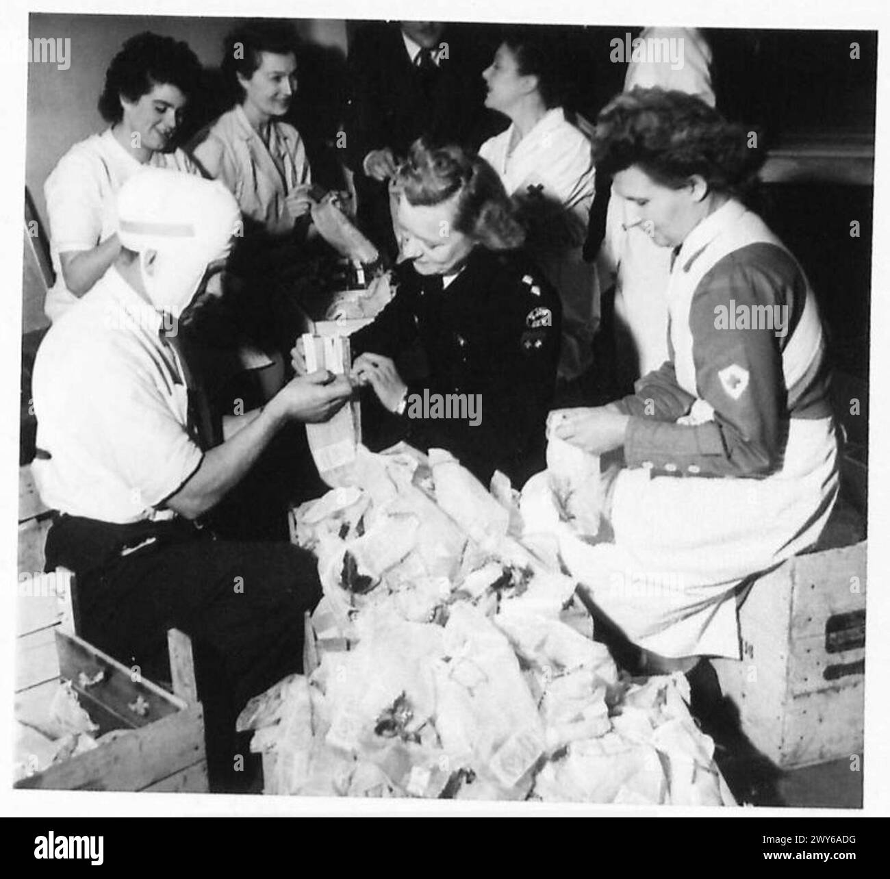 PREPARARSI PER IL NATALE IN Un OSPEDALE GENERALE BRITANNICO - lavoratori della Croce Rossa belga, assistiti da uno dei pazienti, imballare calze pronte per la distribuzione ai pazienti. Uno contrassegnato con 'St. John No. 1." , British Army, 21st Army Group Foto Stock