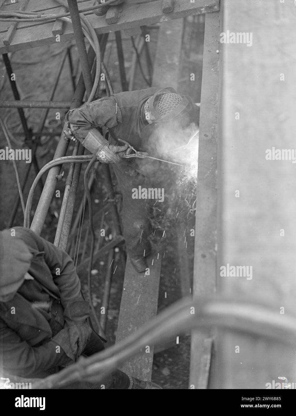 DONNE CHE COSTRUISCONO MEZZI DA SBARCO. 7 APRILE 1944, ALLOA, ROSYTH. UN CANTIERE NAVALE CHE È STATO ABBANDONATO DAL 1918, E DOVE IL 60% DEI LAVORATORI SONO DONNE, STA COSTRUENDO E LANCIANDO MEZZI DA SBARCO PIÙ VELOCEMENTE DI QUALSIASI ALTRO CANTIERE IN GRAN BRETAGNA. ASSEMBLANDO MEZZI DA SBARCO PREFABBRICATI SU QUATTRO POSTI BARCA, UN MEZZO È STATO LANCIATO OGNI SETTE GIORNI NEGLI ULTIMI DUE MESI. - Una giovane donna sposata, una volta lavoratrice in un mulino di lana, ora è una saldatrice esperta. , Foto Stock