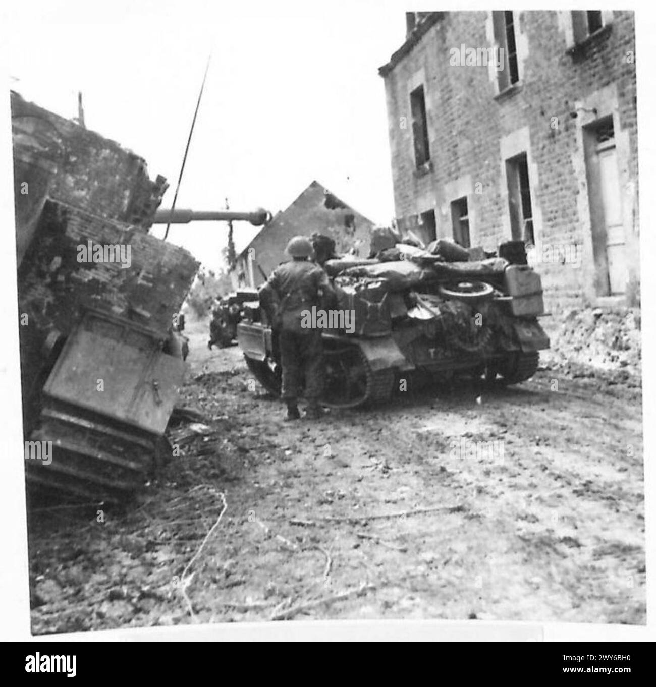 Una portaerei Bren si sposta davanti a un carro armato tedesco distrutto a Rauray durante l'offensiva britannica in Francia, coinvolgendo il 2nd Battalion Kensingtons, British Army, 21st Army Group. Foto Stock