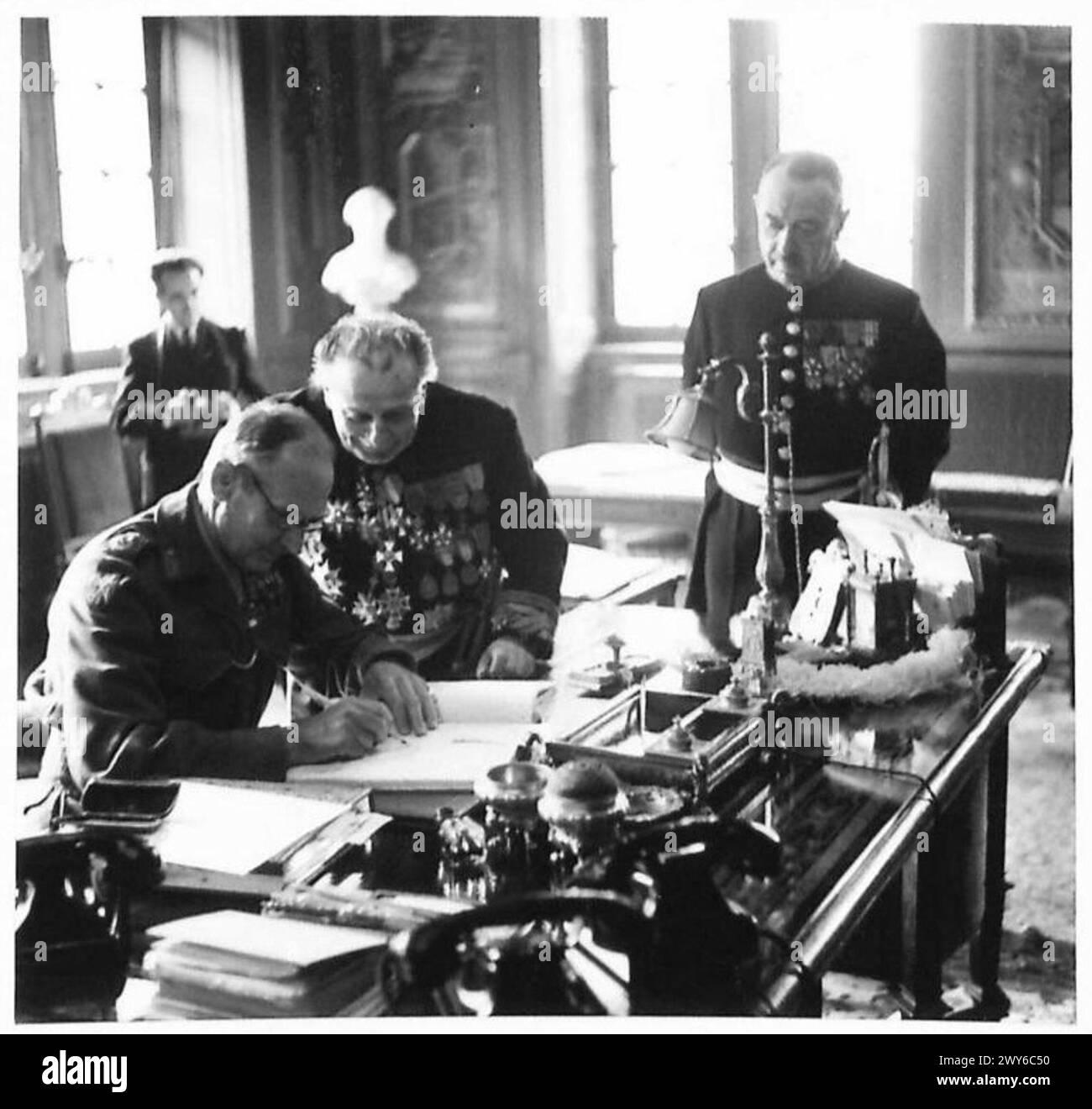 Il feldmaresciallo Montgomery, assistito da Brussels Burgomaster M. Van de Moulebroeck, firma il libro d'oro all'Hotel de Ville durante le operazioni dell'esercito britannico del Reno. Foto Stock