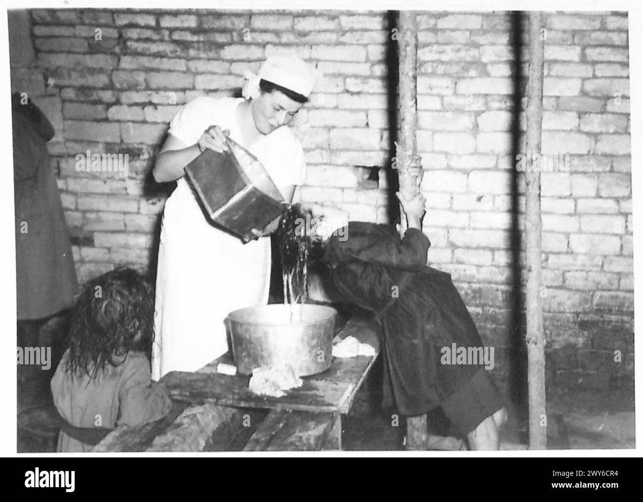 I bambini che arrivano in un campo di transito del 21st Army Group dell'esercito britannico vengono lavati e trattati dagli infermieri dopo l'esposizione a condizioni difficili, tra cui No Man's Land e rifugi improvvisati, con conseguenti condizioni verminose. Foto Stock