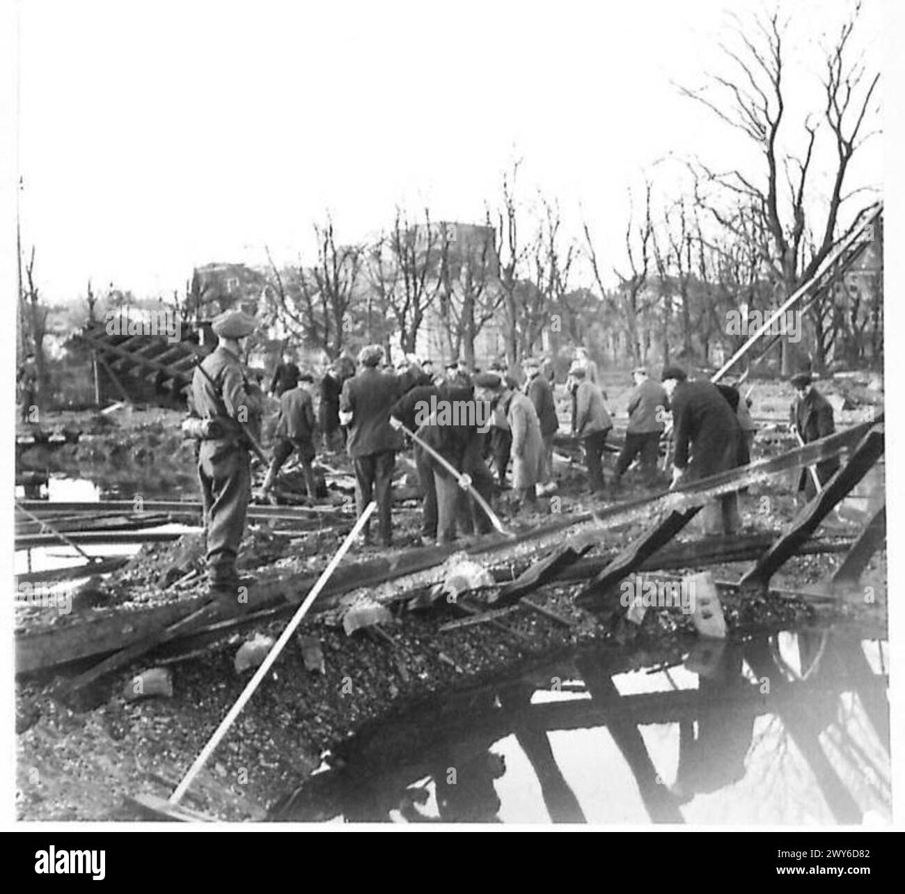 I civili tedeschi, supervisionati dalle guardie armate britanniche, ripararono una strada sopra un cratere bomba alla stazione ferroviaria di Kleve durante l'occupazione alleata. Foto Stock