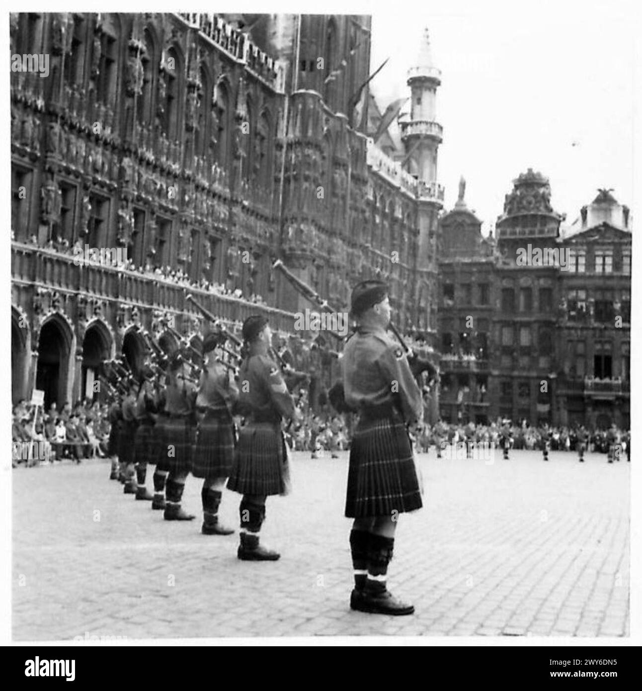 Una banda di pipe marcia in un unico file a Bruxelles con l'Hotel de Ville visibile sullo sfondo durante un evento militare. Foto Stock