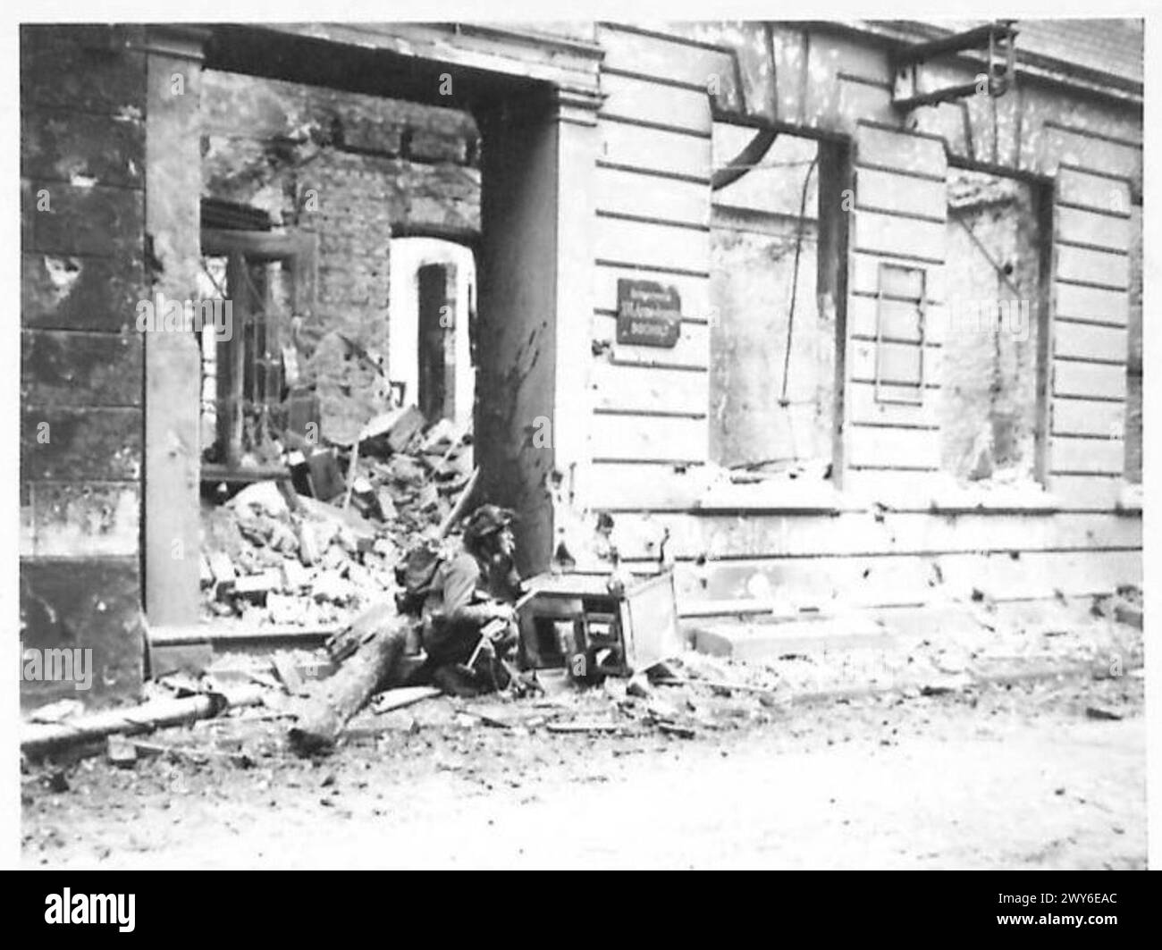 COMBATTIMENTI IN STRADA A BOCHOLT - un fanteria accovacciato dietro una stufa da cucina pronta a ripararsi da Spandau o dal fuoco di un proiettile. , British Army, 21st Army Group Foto Stock