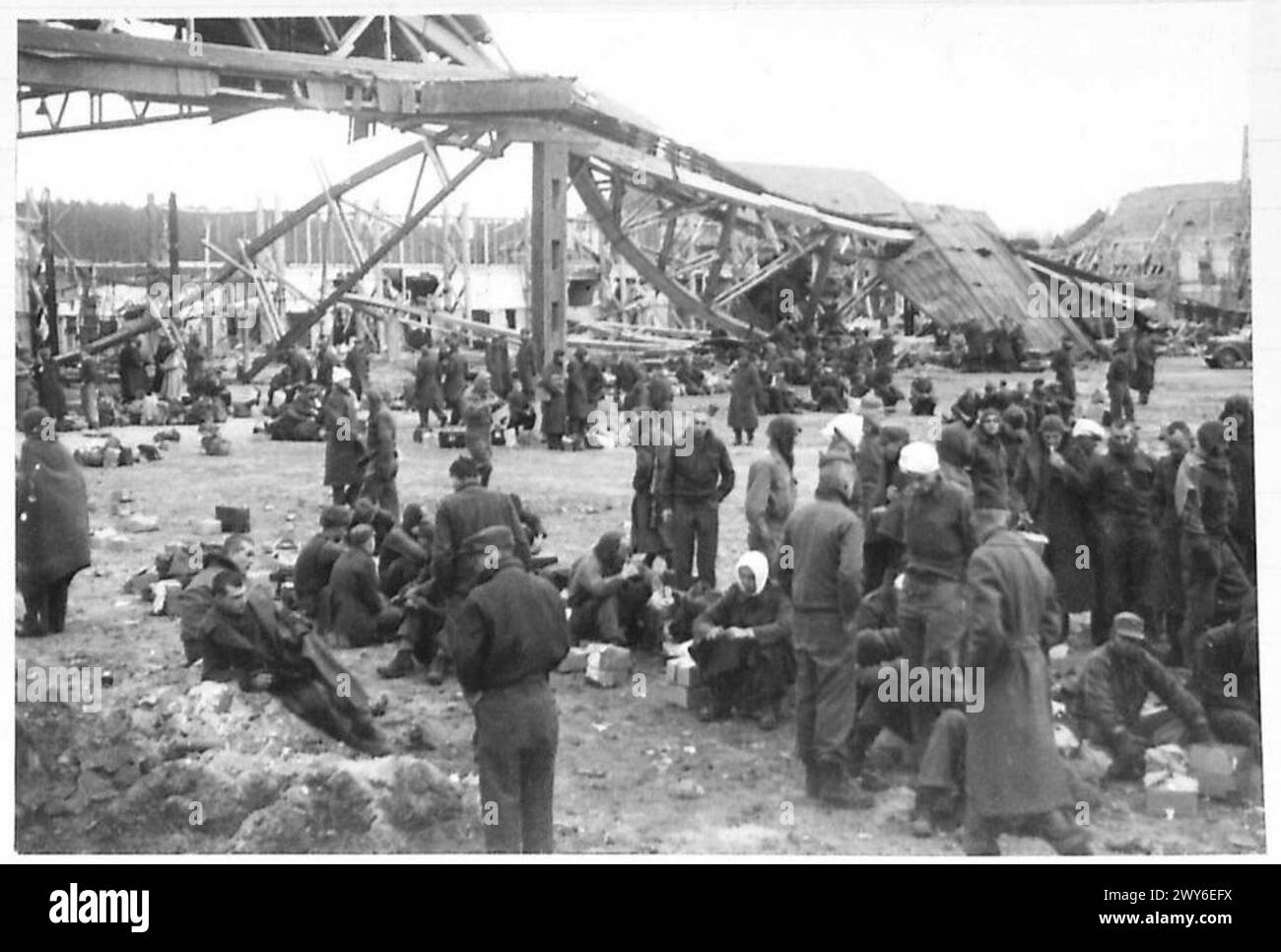 PRIGIONIERI OFLAG RILASCIATI DALLE TRUPPE AMERICANE - presso l'aerodromeat distrutto i prigionieri di Geissen siedono e si fermano in lotti in attesa di aerei che li faranno volare a casa. , British Army, 21st Army Group Foto Stock