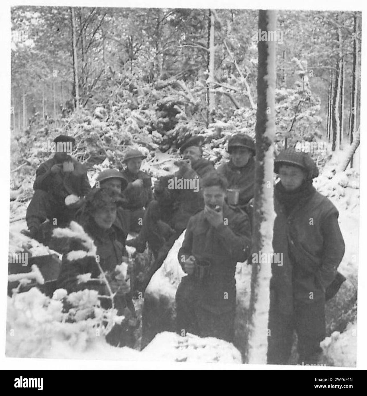 Un gruppo di soldati britannici del 21st Army Group pranzano fuori dai loro dugouts durante le operazioni, mostrando un momento di riposo in mezzo ai doveri militari. Foto Stock