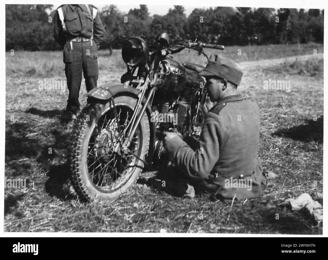 I prigionieri catturati nei pressi di Conde-sur-Noireau in Normandia trascorrono del tempo a pulire jeep e motociclette vicino alla gabbia dei prigionieri di guerra mentre sono sotto la supervisione britannica. Foto Stock