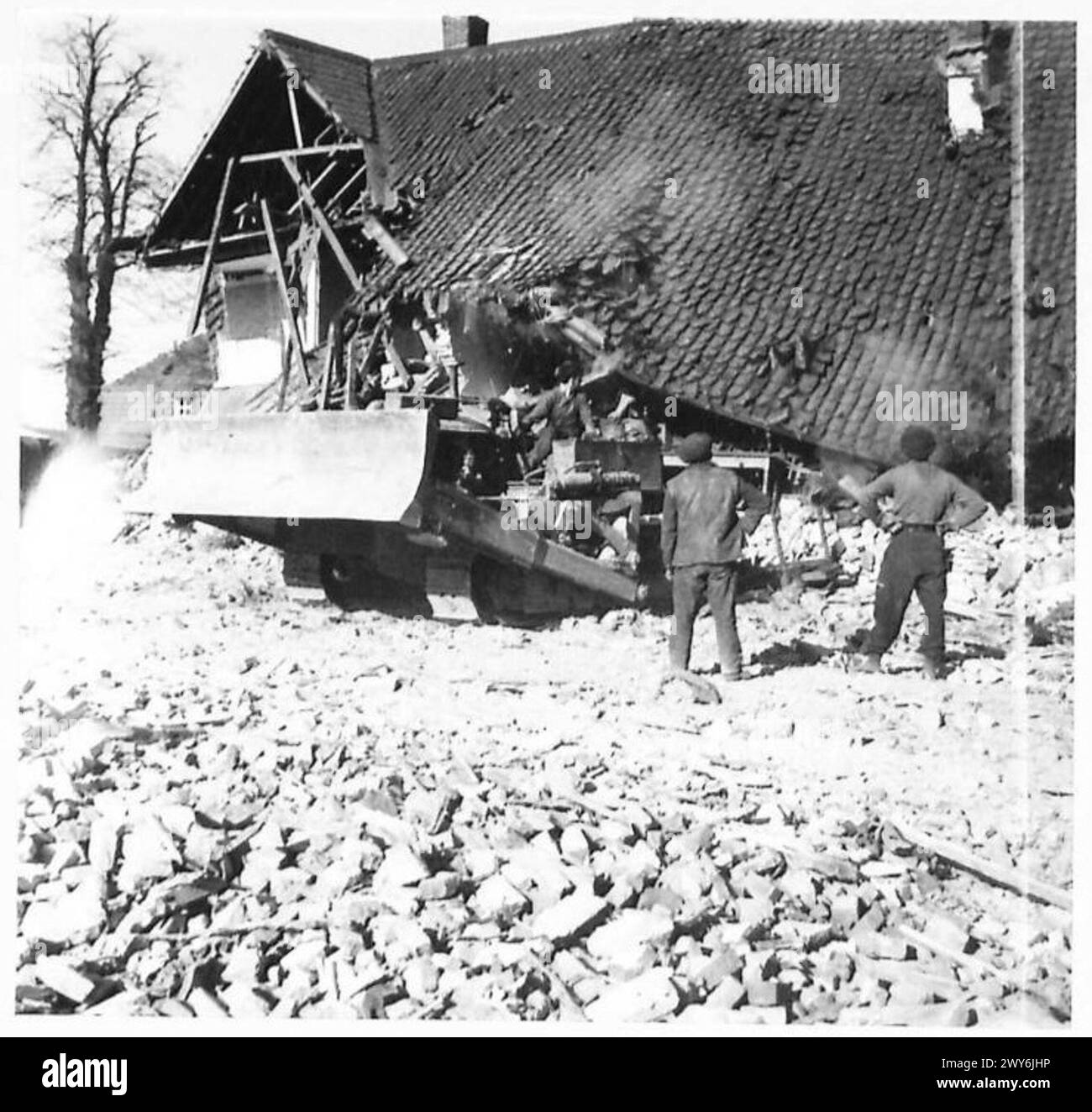 Un bulldozer demolisce parte di una casa durante i lavori di miglioramento della strada in un'area controllata dai militari. Foto Stock