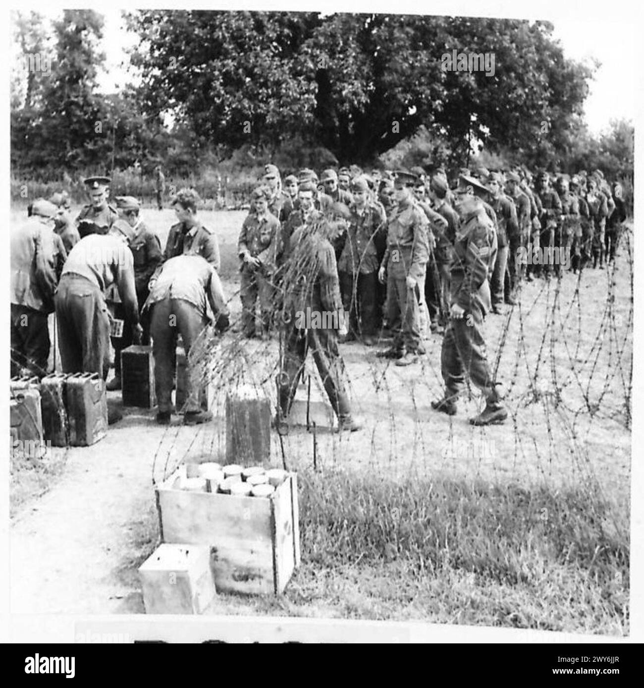 I prigionieri di guerra tedeschi ricevono razioni all'interno di una gabbia di prigionieri di guerra sotto la supervisione dell'esercito britannico durante la seconda guerra mondiale Foto Stock