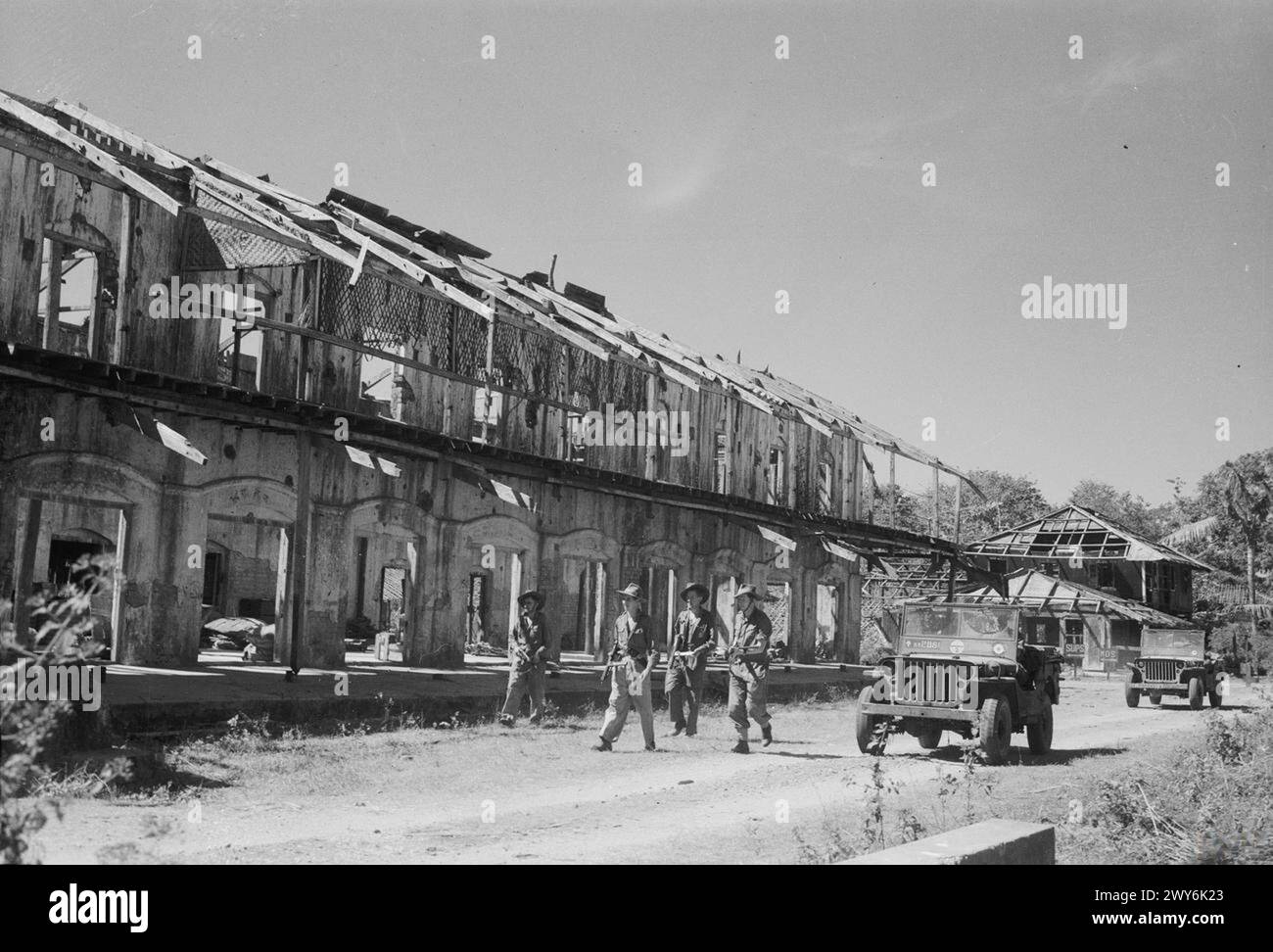 Il gruppo d'assalto della Royal Air Force avanza oltre un edificio danneggiato da una bomba dopo gli sbarchi sull'isola Ramree durante la campagna di Arakan della campagna di Birmania 1941-1945. Foto Stock