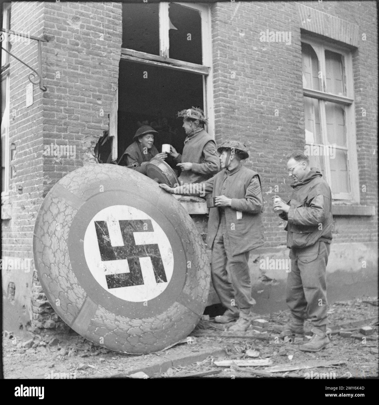 Le truppe britanniche si fermano per il tè a Kranenberg il 9 febbraio 1945, vicino a un grande emblema circolare di svastica durante la campagna dell'Europa nordoccidentale. Foto Stock