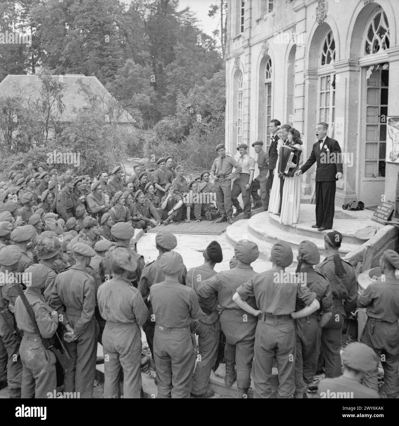 Gli artisti della E.N.S.A intrattenevano le truppe in Normandia utilizzando i gradini di un castello, precedentemente un quartier generale tedesco, come palcoscenico durante la seconda guerra mondiale Foto Stock Gli artisti della E.N.S.A intrattenevano le truppe in Normandia utilizzando i gradini di un castello, precedentemente un quartier generale tedesco, come palcoscenico durante la seconda guerra mondiale Foto Stock