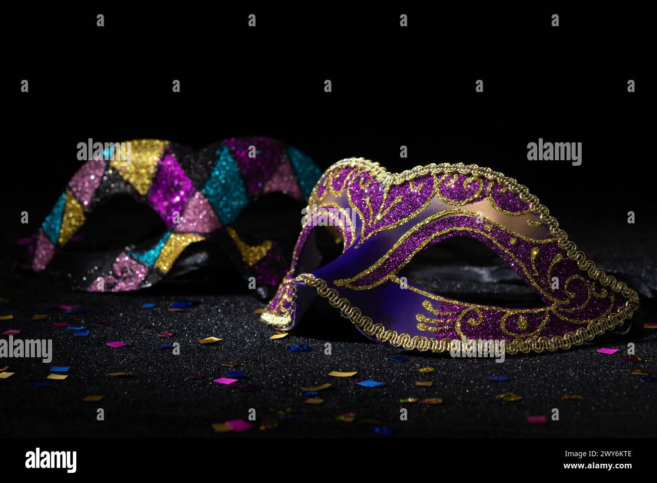 Vista ravvicinata della maschera mascherata con confetti su sfondo nero. Foto Stock