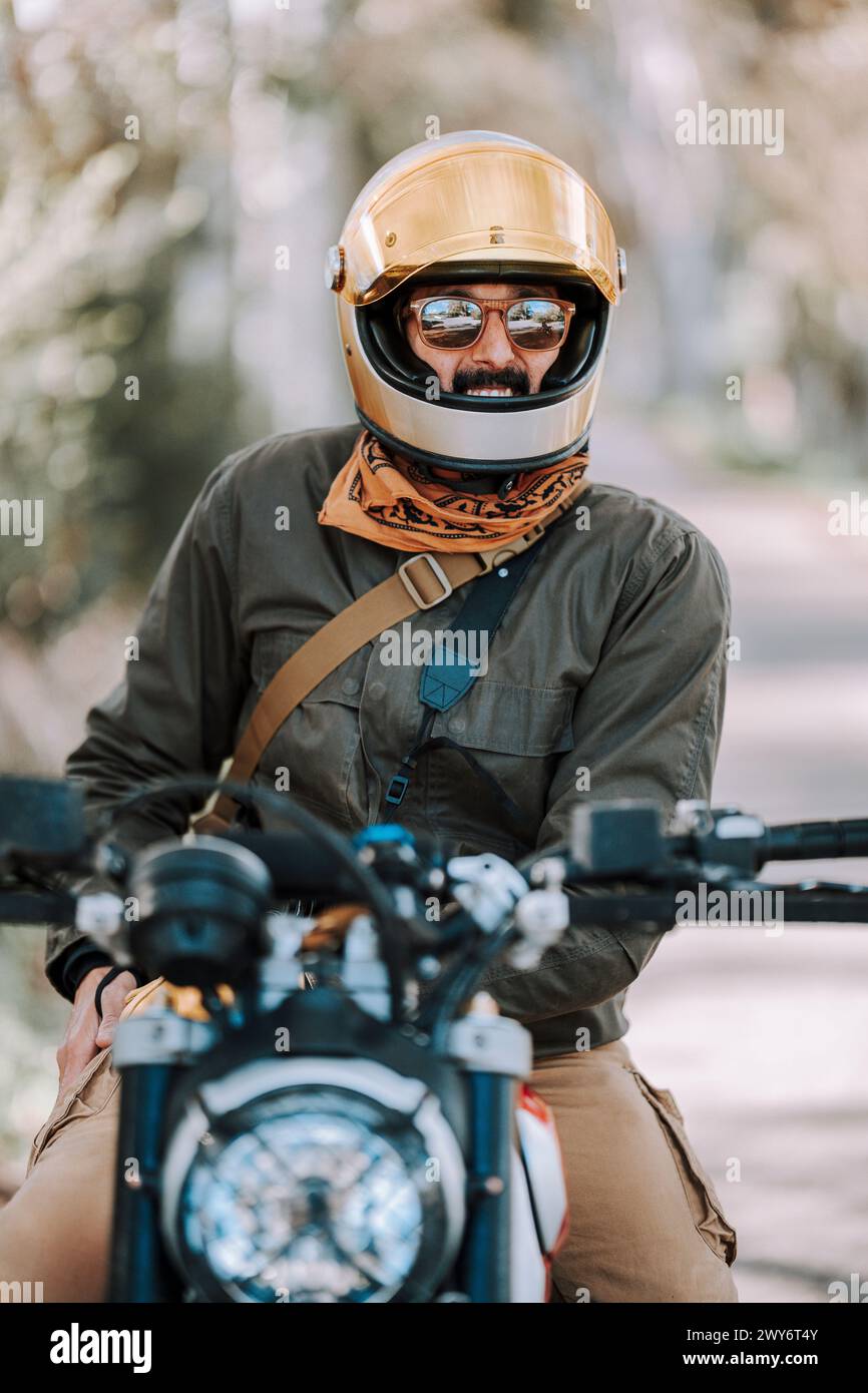 Il motociclista con casco siede su una bicicletta con sedile posteriore rialzato Foto Stock