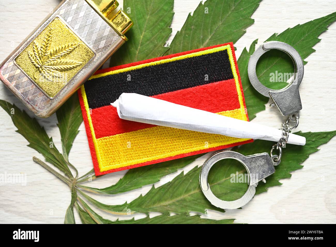 Joint und Deutschland-Fahne auf Cannabis-Blatt mit Handschellen, Cannabis-Legalisierung *** bandiera congiunta e Germania su foglia di cannabis con manette, legalizzazione della cannabis Foto Stock