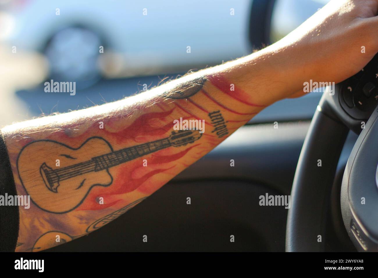 Parti per un viaggio in cui l'arte incontra il movimento mentre un braccio tatuato comanda la ruota con sicurezza e stile Foto Stock