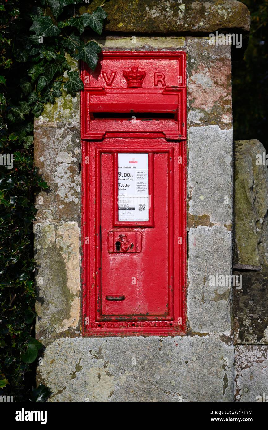 Shawbury, Regno Unito - 18 marzo 2024; casella postale rossa inglese nel muro con lettere della Regina Vittoria Foto Stock