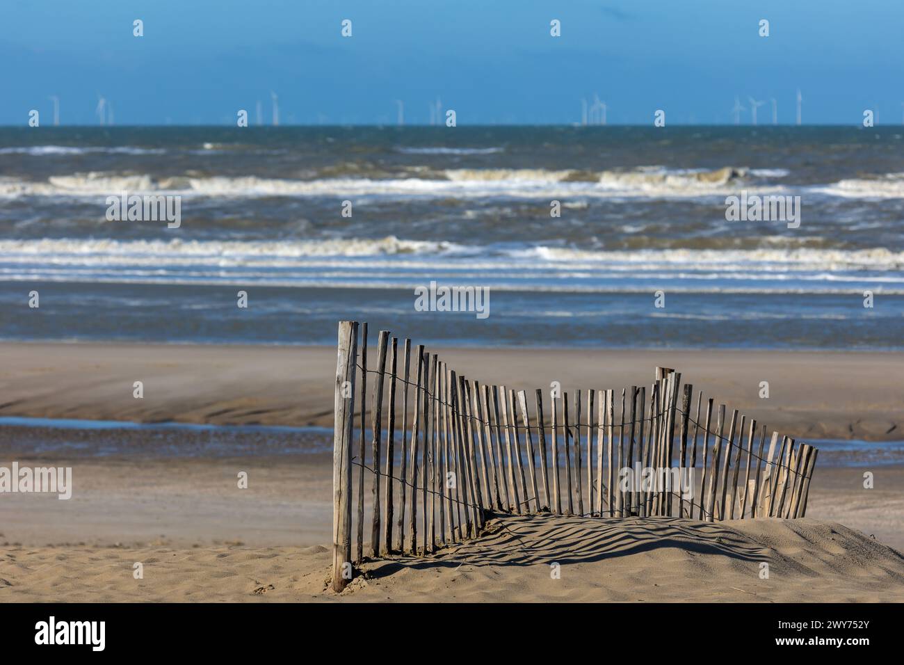 Una palpitante recinzione sulla spiaggia del Mare del Nord vicino a Egmond aan Zee, Paesi Bassi, di fronte a un mare accidentato con onde spinose Foto Stock