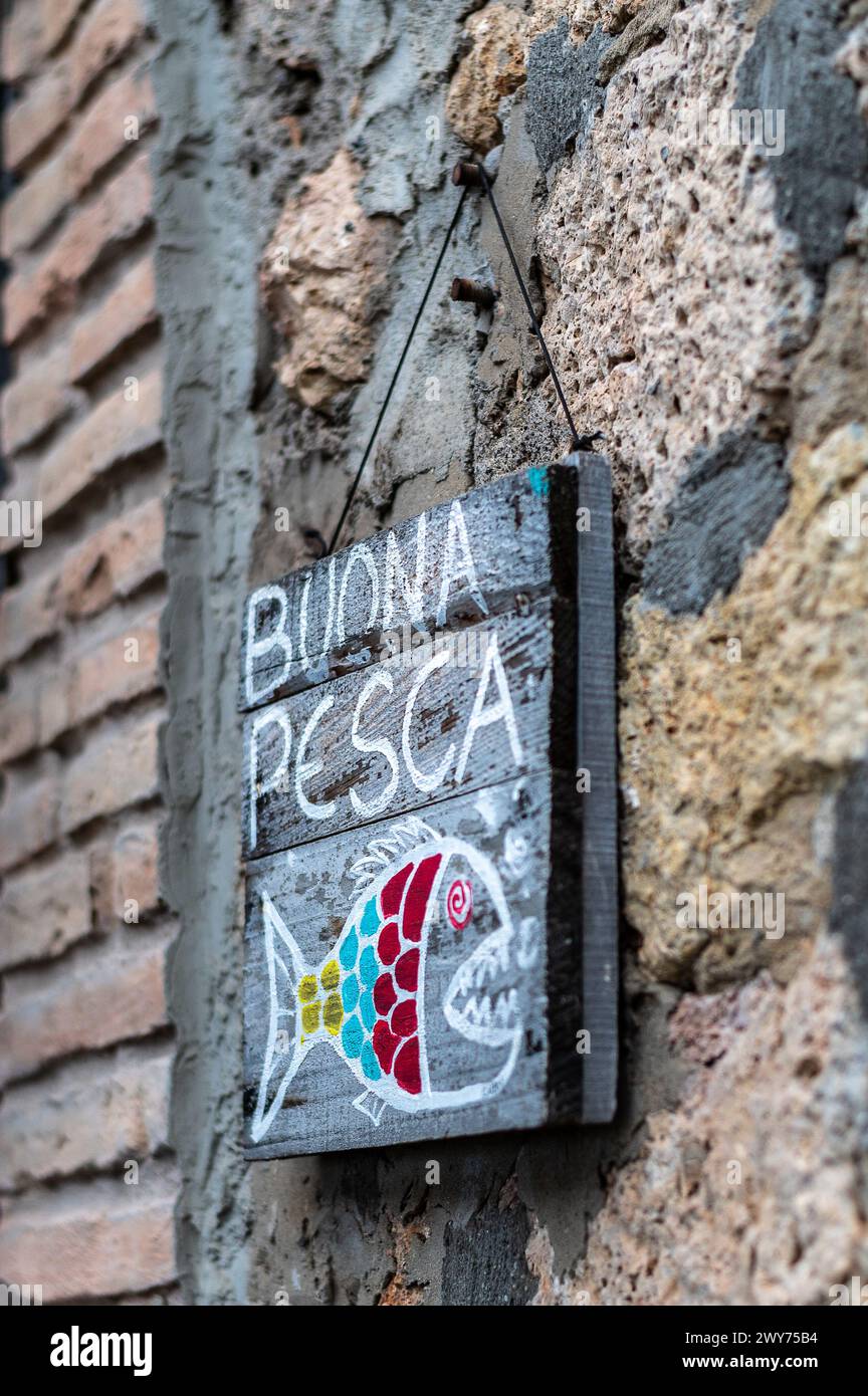 Un'immagine verticale di un cartello artistico su un muro di pietra per un ristorante di pesce sulla costa toscana Foto Stock