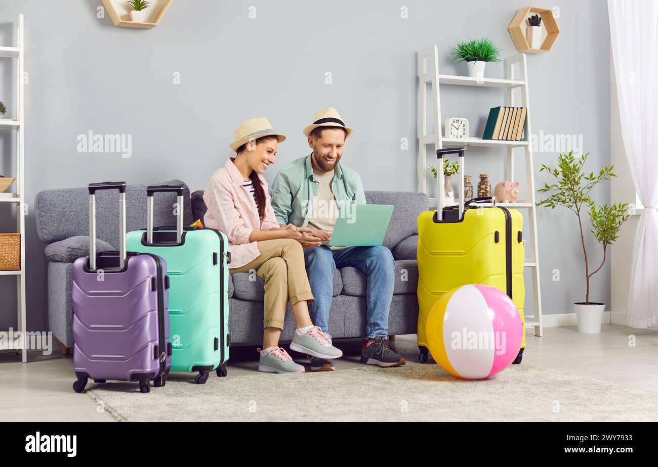 Coppia entusiasta che usa il laptop per prenotare biglietti e hotel online, preparandosi per le vacanze. Foto Stock