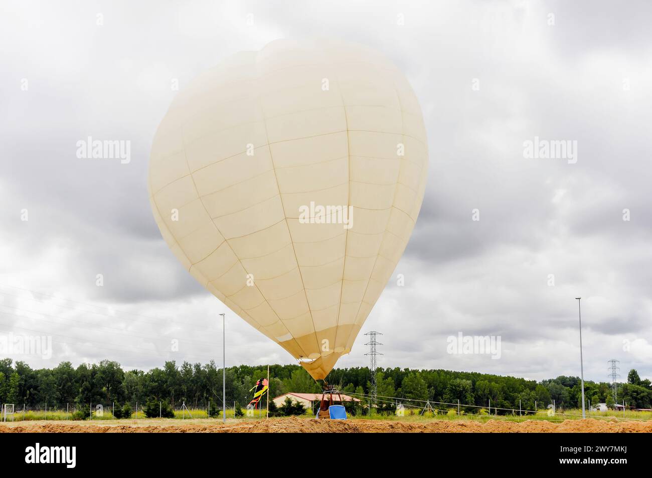 Pallone aerostatico arroccato a terra in un campo durante una giornata nuvolosa. Mongolfiera. Foto Stock
