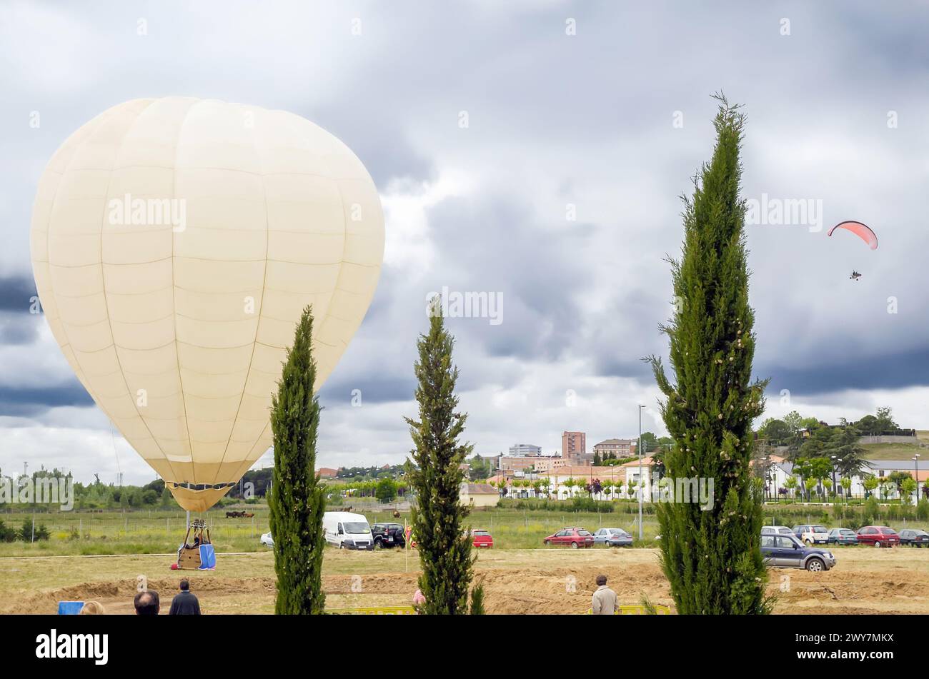 Mongolfiera sul terreno di un campo e paramotore che volano nel cielo durante un evento di svago vicino alla città. Foto Stock