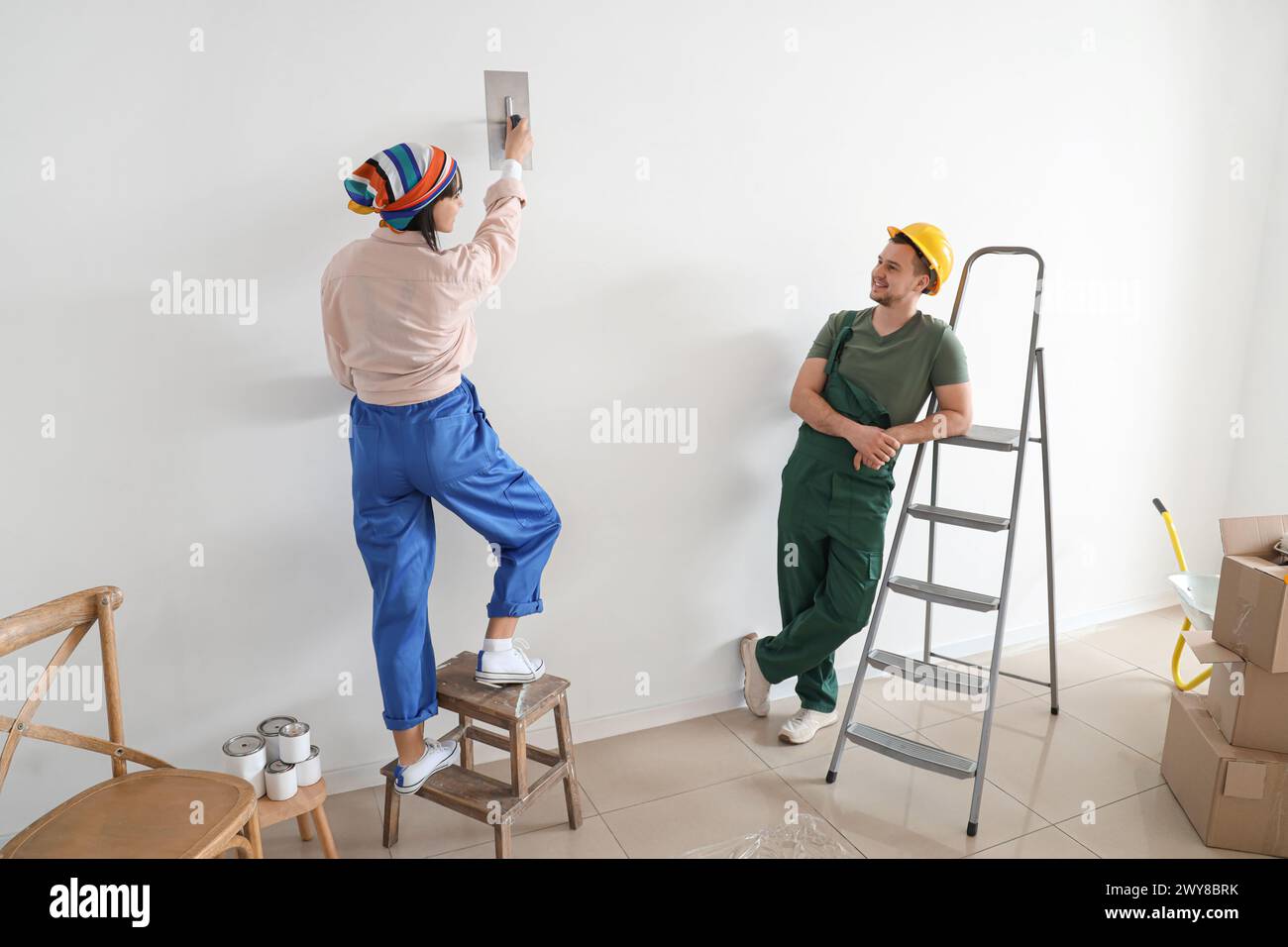 Una giovane coppia che si schianta contro il muro durante le riparazioni nella loro nuova casa Foto Stock