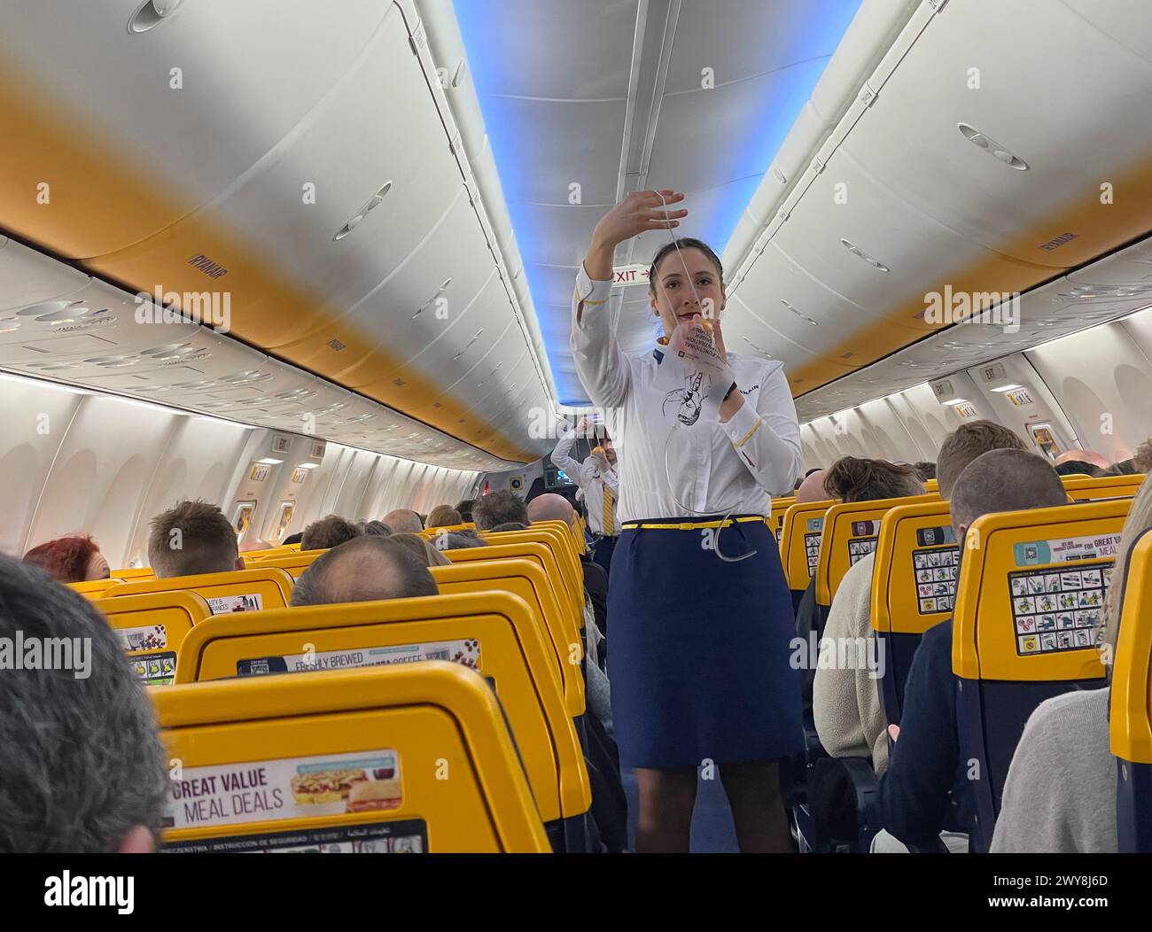 Un assistente di volo dimostra le procedure di sicurezza a bordo di un volo Ryan Airlines. Foto Stock