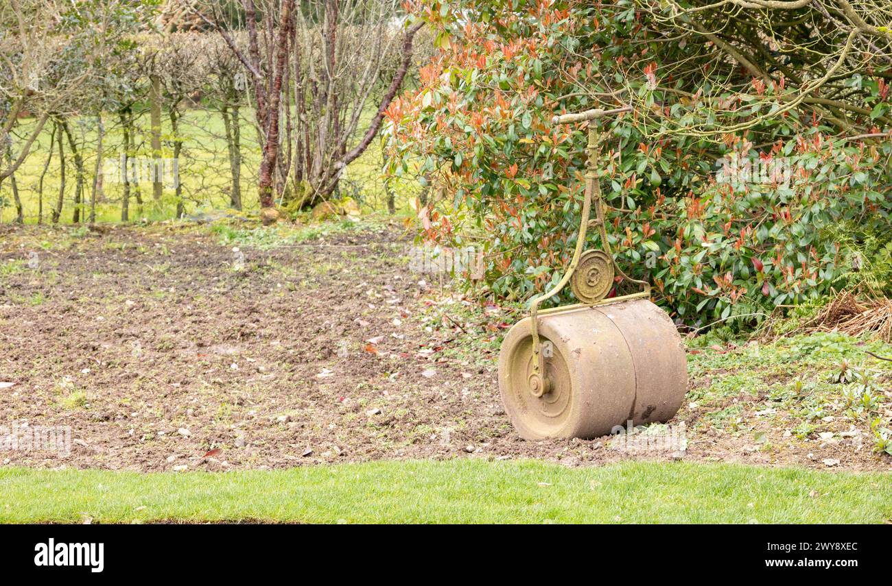 Vecchie attrezzature da giardino, un rullo da giardino manuale, un progetto da giardino primaverile, un rullo in metallo vintage Foto Stock