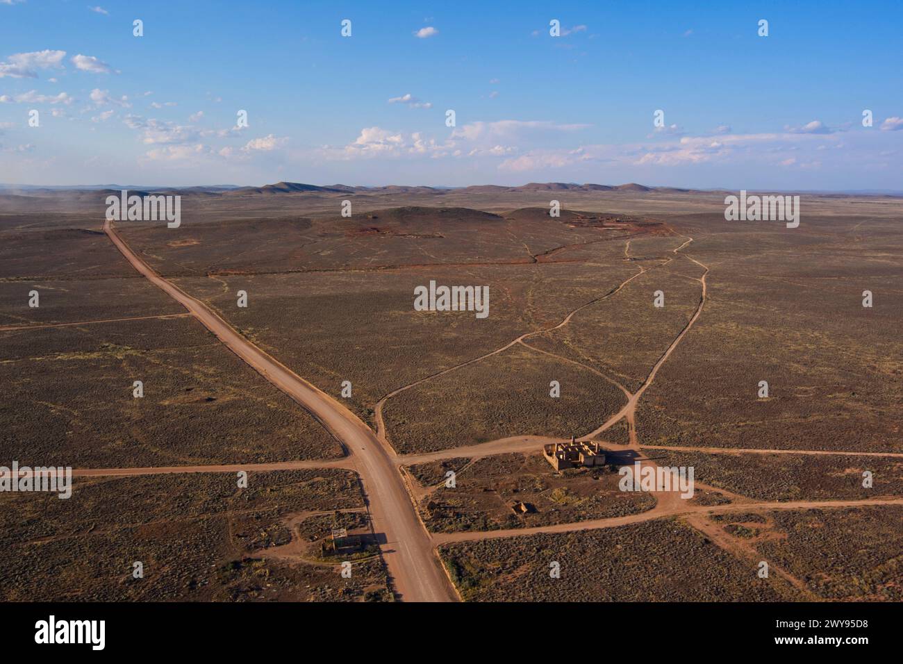 Vista aerea di un vasto e arido paesaggio con strade sterrate intersecanti e vegetazione minima sotto un cielo blu Foto Stock