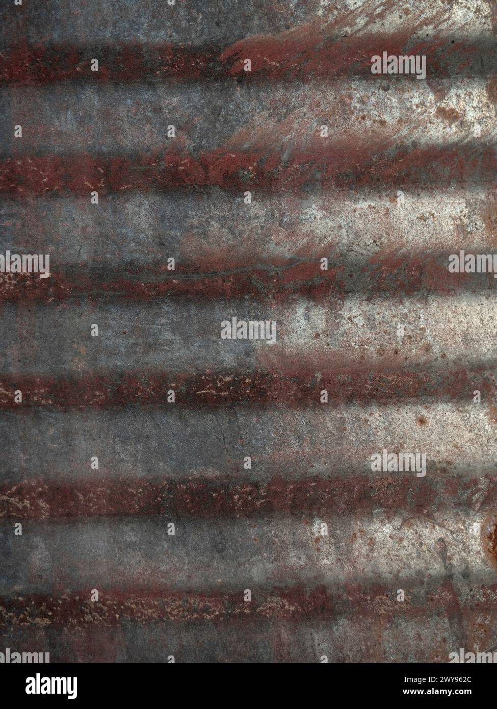 Tamburo in ferro ondulato industriale con sei anelli rossi arrugginiti sullo sfondo con spazio di copia. Foto Stock