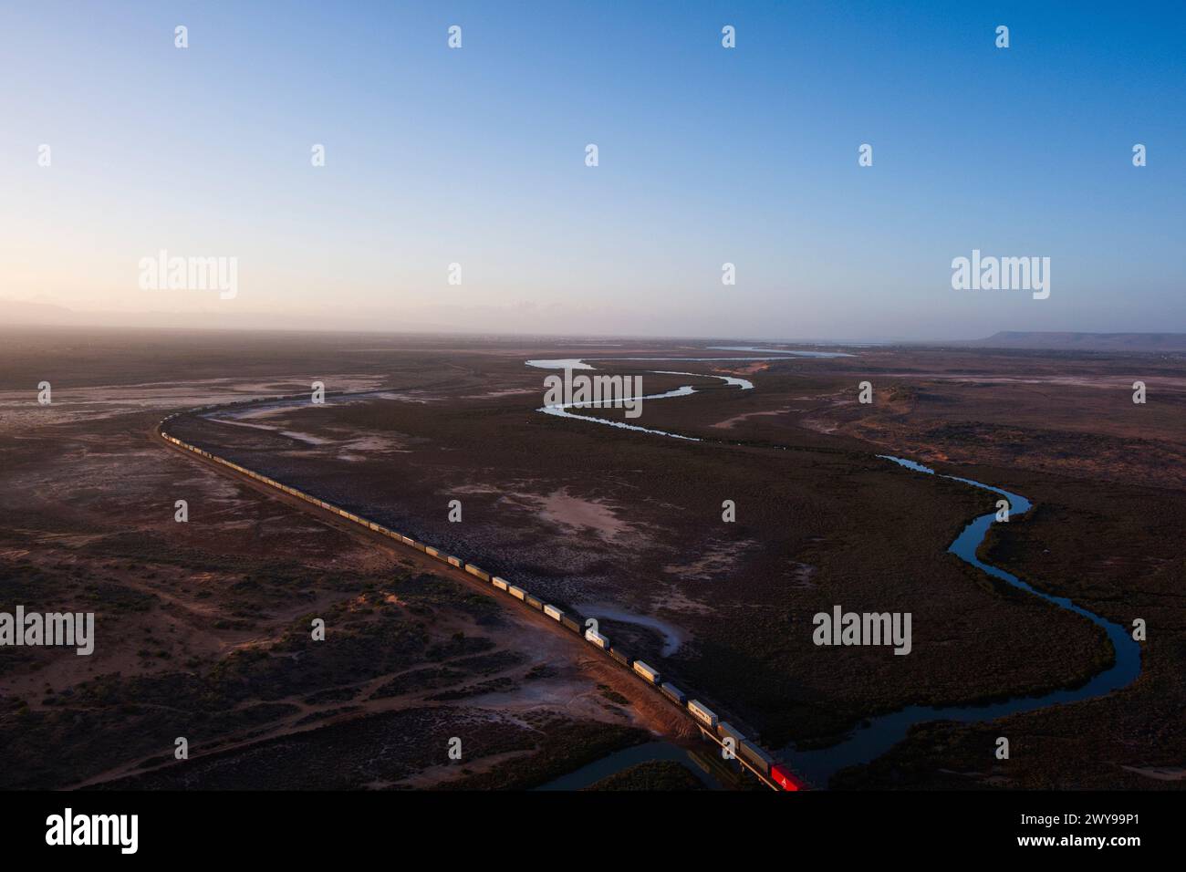 Vista aerea di un treno merci intermodale che attraversa un vasto paesaggio desertico al crepuscolo vicino a Port Augusta, Australia meridionale Foto Stock