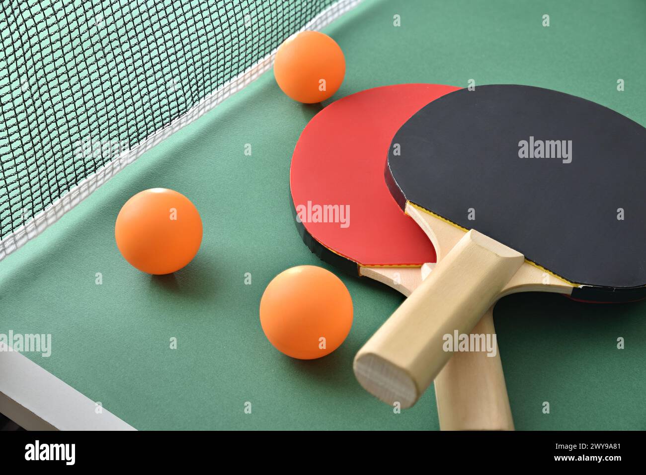 Set di pale da ping pong e pallina arancione sul tavolo da gioco verde. Vista rialzata. Foto Stock