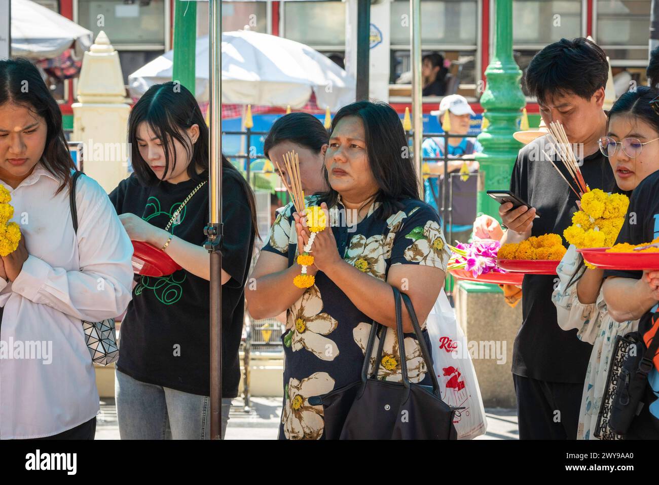 Nel centro di Bangkok, un incontro eterogeneo di turisti e locali thailandesi converge al Santuario di Erawan, ciascuno impegnato in preghiera con le proprie offerte. Bangkok, Thailandia. Foto Stock