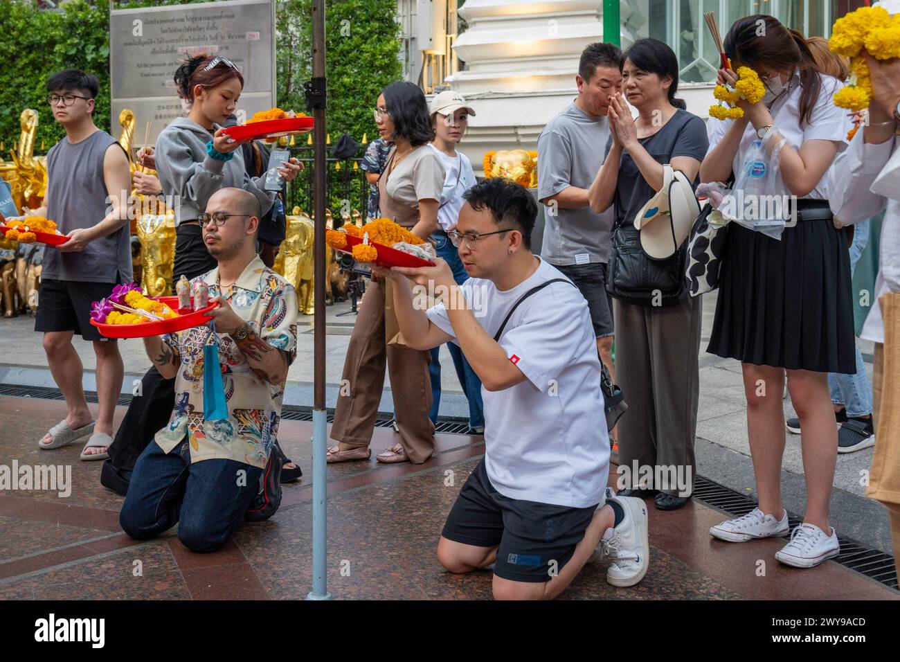 Al Santuario Erawan nel centro di Bangkok, un asiatico sta pregando con un cestino di offerte in mano tra la folla. Bangkok, Thailandia. Foto Stock