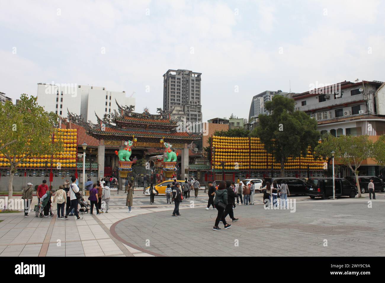Taipei, Taiwan - 17 marzo 2024: Porta d'ingresso al Tempio di Longshan, Taipei. Strada trafficata, visitatori, gente del posto, lanterne, grattacieli. I tempi moderni mee Foto Stock