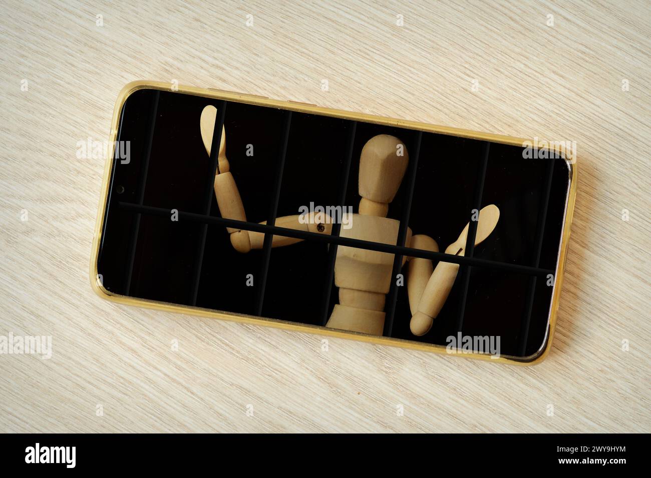 Smartphone con prigioniero in legno dietro le sbarre - concetto di dipendenza da tecnologia e dispositivi mobili Foto Stock
