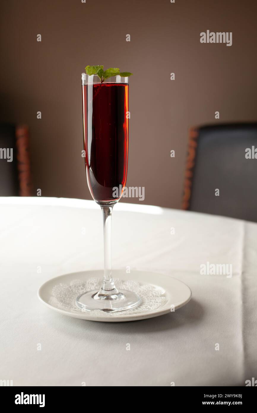 Bicchiere sottile con cocktail rosso e guarnire seduti sul tavolo Foto Stock