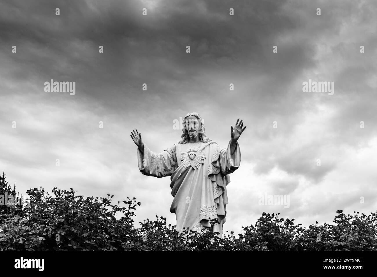 Statua di Gesù con cielo nuvoloso in bianco e nero Foto Stock