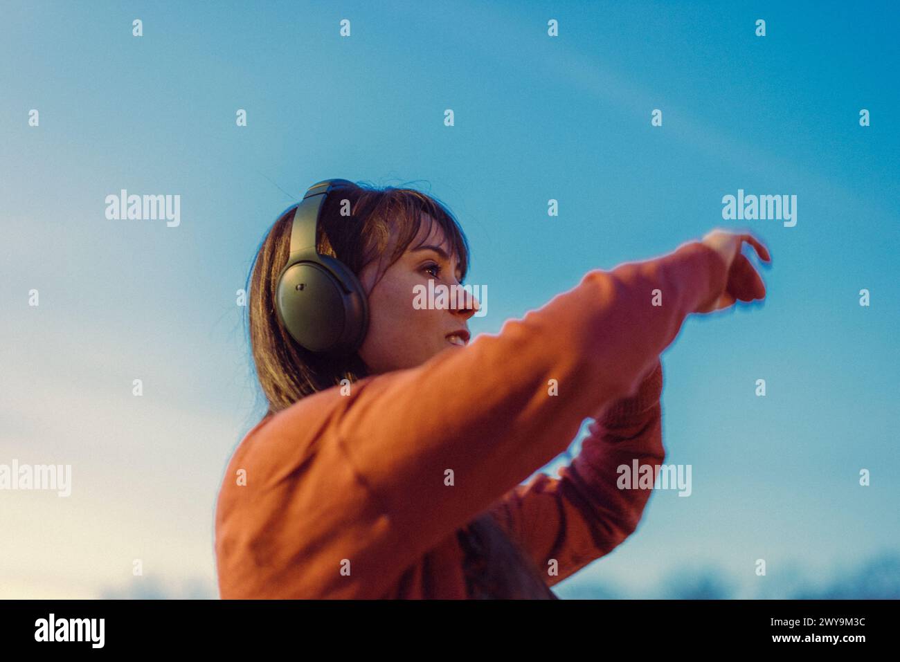 La giovane donna indossa cuffie e balla con la musica al tramonto. Foto Stock