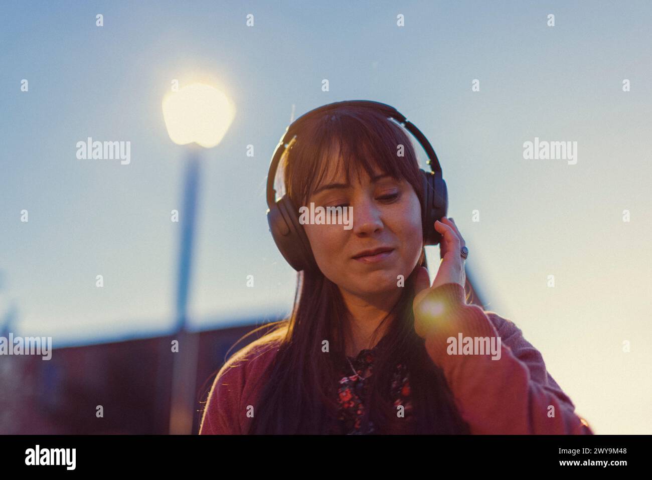 La giovane donna indossa cuffie e balla con la musica al tramonto. Foto Stock