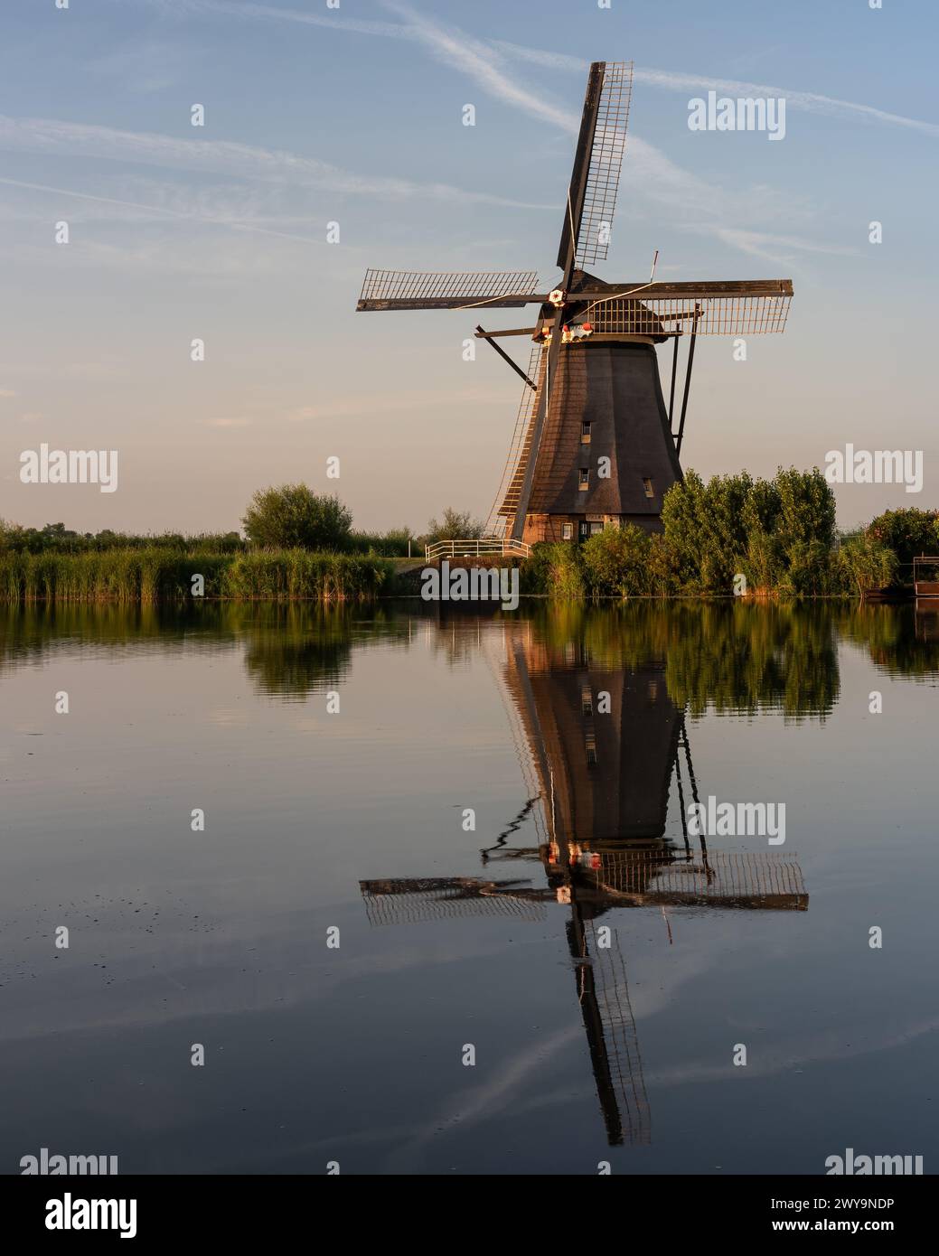 Un vecchio mulino a vento che si riflette nell'acqua serena. Kinderdijk, Paesi Bassi Foto Stock