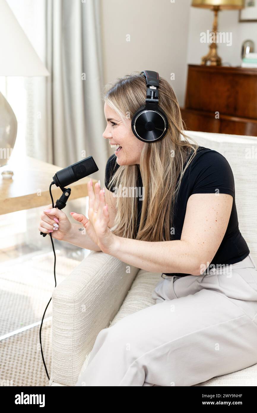 Podcasting donna gioiosa con microfono e cuffie Foto Stock