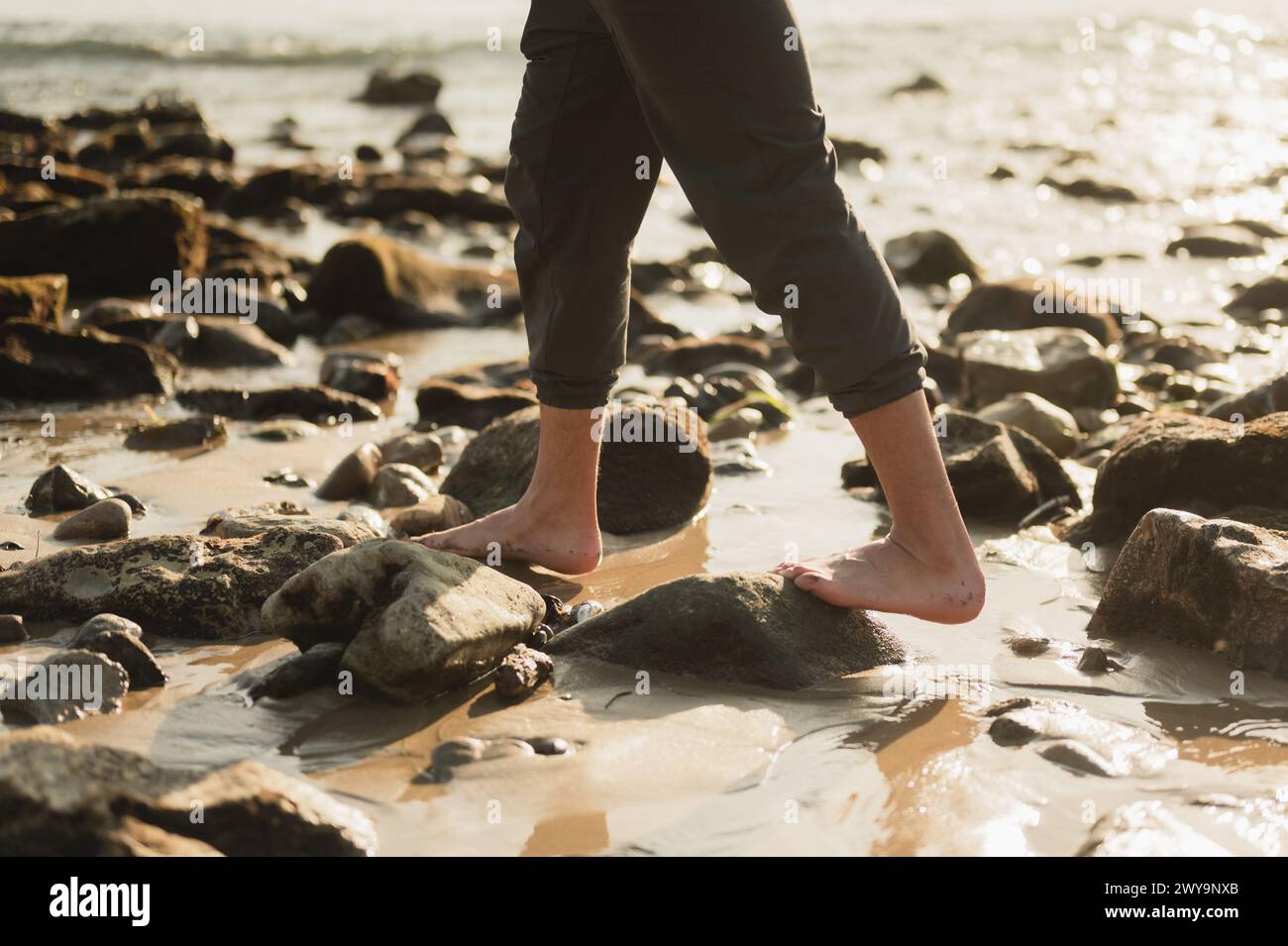 Uomo che cammina sulle rocce della spiaggia lungo la costa dell'oceano in California Foto Stock