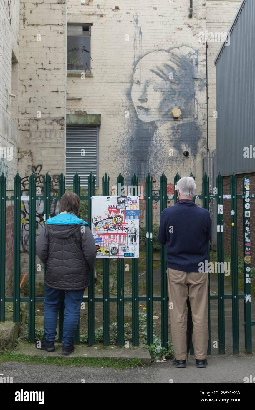 Due persone che guardano Banksys Girl con un timpano trafitto Foto Stock