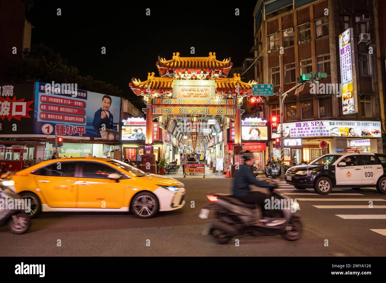 Una scena notturna della città con luci luminose di auto e cartelli dei negozi, che mostrano la vivacità della vita notturna urbana di Taipei Foto Stock