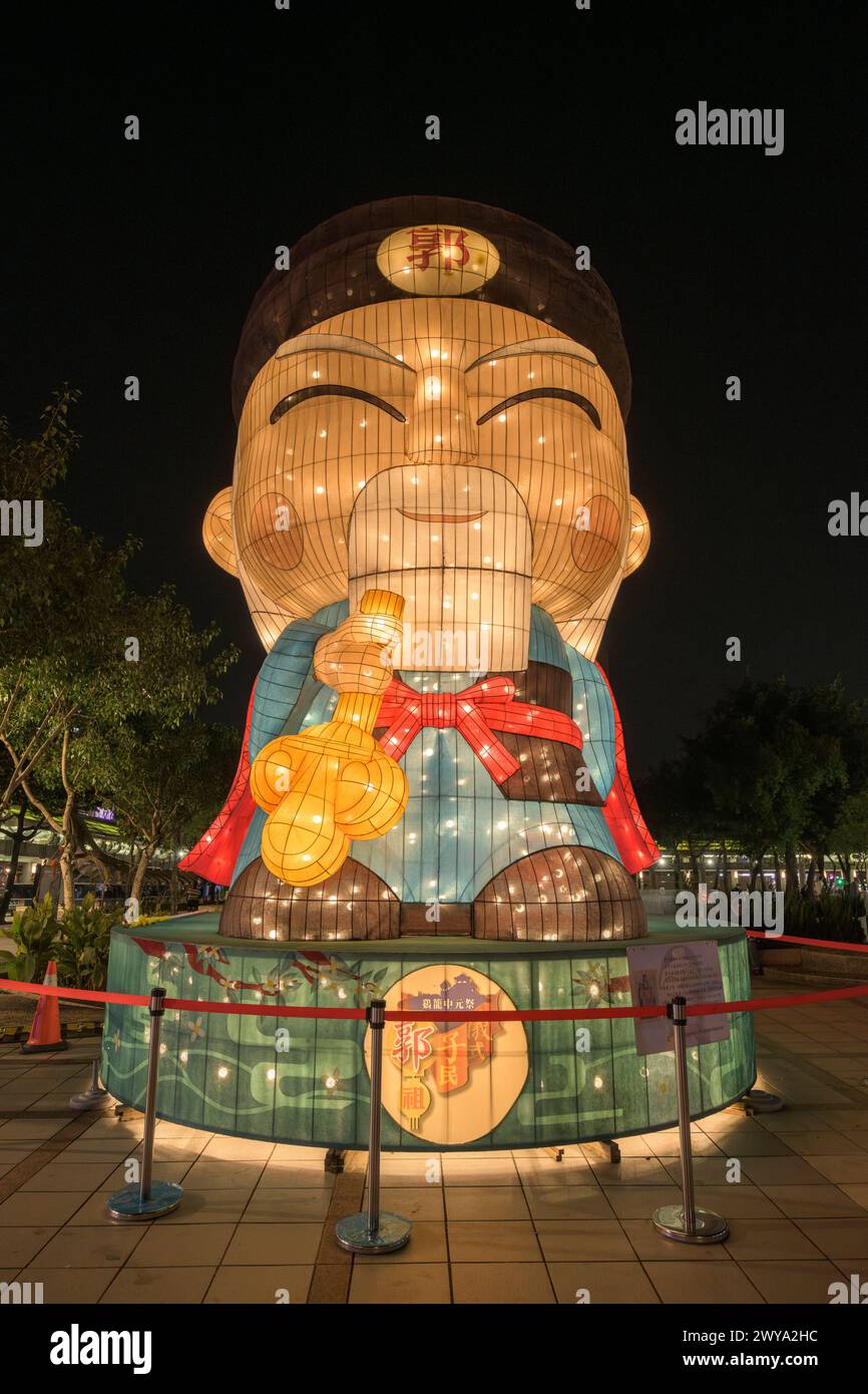 Una lanterna su larga scala, molto illuminata, di una figura tradizionale che regala delizia ai visitatori del tempio Longshan Foto Stock